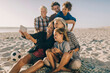 © Marko Geber - Happy family taking selfie on beach with soccer ball