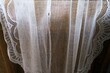 Alte weiße transparente Gardine vor brauner Holztür mit Licht und Licht als Hintergrund
