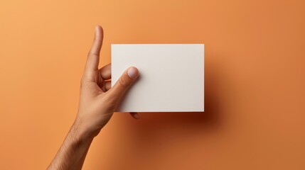 Poster - A hand holding a square piece of paper against an orange wall, AI