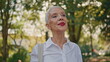 Happy senior walking outdoors closeup. Beautiful grey hair woman in green park