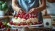 Person preparing cake with fresh berries and raspberries
