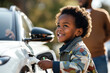 © kossovskiy - Electric car charging smiling boy
