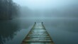 The solitary wooden pier stretches into the serene lake, where fog veils the distant horizon in mystery.
