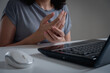 woman holding her wrist pain from using a laptop computer long time. Carpal tunnel syndrome or wrist joint inflammation, arthritis, neurological disease, Numbness hand, office syndrome.