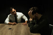 © AntonioDiaz - Focused detective interviews a distressed man in a dimly lit interrogation room