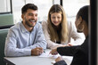 © fizkes - Happy married couple signing real estate property buying agreement, writing in document, meeting with broker, banker, agent at table, talking to consultant, smiling, laughing