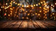 At night time, a wood table top stands empty with decorative string lights hanging from a garden tree, casting a blur of bokeh light in the background, akin to fairy lights.