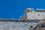 Fototapeta Desenie - The imposing ruins of the Parthenon atop the rocky Acropolis under a bright blue sky in Athens Greece
