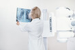 A female doctor looks at an x-ray of the ribs and lungs against the background of x-ray equipment. Diagnosis of Covid, exclusion of pneumonia. Skeleton bones on x-ray