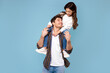 Father's love. Happy daddy carrying his daughter on shoulders posing and having fun on blue studio background