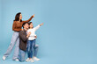 © Home-stock - Great offer. Cheerful european family, parents and girl, pointing fingers upward at empty space, standing over blue studio background
