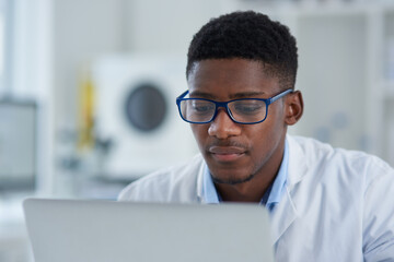 Poster - Science, reading and black man with laptop, glasses pharmaceutical research in laboratory. Medical study, lab technician or scientist on computer for online review, report or checking results on web.