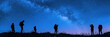 Silhouettes of people stargazing against a night sky.