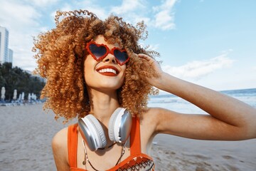 Wall Mural - Summer Bliss: Smiling Woman on Beach, Embracing Freedom and Nature with Curly Hair and Freckles, Listening to Music with Headphones, Exuding Happiness and Joy Outdoors