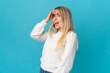 Young blonde woman isolated on blue background doing surprise gesture while looking front