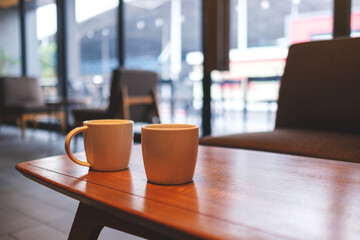 Wall Mural - Two white cups of hot coffee on wooden table in cafe