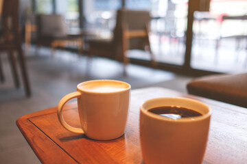 Wall Mural - Two white cups of hot coffee on wooden table in cafe