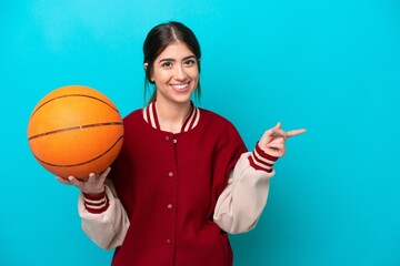 Wall Mural - Young caucasian basketball player woman isolated on blue background pointing finger to the side