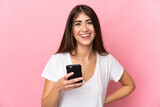 Fototapeta  - Young caucasian woman isolated on pink background using mobile phone