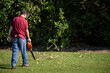 Man cleaning autumn leaves using a leaf blower on the lawn. Auckland.