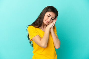 Wall Mural - Young caucasian woman isolated on blue background making sleep gesture in dorable expression