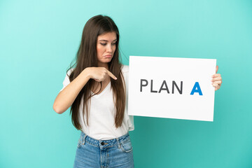 Wall Mural - Young caucasian woman isolated on blue background holding a placard with the message PLAN A and  pointing it