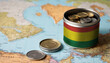 A jar filled with cash, displaying the Bolivia flag, sits atop a map. Saving for vacation, leisure activities. Financial planning, travel budget allocation