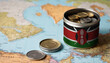 A jar filled with cash, displaying the Kenya flag, sits atop a map. Saving for vacation, leisure activities. Financial planning, travel budget allocation