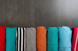 close up of rolled colorful t shirt clothes on black table background, travel and lifestyle concept