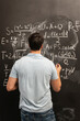 © Vitaliy - Physics teacher writes various formulas on the blackboard