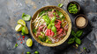A top-down view of a traditional Vietnamese beef pho bo soup served in a white bowl, adorned with soy sprouts, fresh cilantro, sliced lime, and accompanied by a pair of chopsticks. 