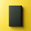 Top view of a closed black hardcover book on a yellow background