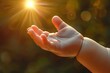 A newborn babys hand reaching out to grasp a sunbeam, symbolizing the beginning of a spiritual journey