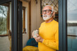 © Miljan Živković - One senior man stand in at door of tiny house happy smile hold cup
