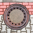 Rusty iron hatch in the city on the sidewalk. Waste water urban communication, detail of round iron cover in pavement gray and brick pavement.