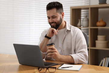 Poster - Young man with cup of coffee watching webinar at table in room