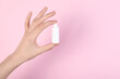 Woman with bottle of medical drops on pink background, closeup