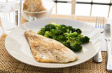 Fototapeta Koty - Fried fillet of sea bass with garnish of broccoli on black warm stone plate