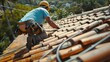Roof tiles are being installed on the roof of a house by a construction worker