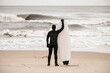 Slender male surfer stands on the seashore and holds his surfboard