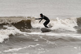 Fototapeta  - Male surfer riding a surfboard on a high wave, keeping his balance