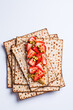 Matza toast with peanut butter, strawberries and pistachios on a white plate. Traditional bread for the Jewish holiday of Passover.