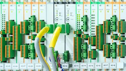 Poster - A bunch of wires and plugs are connected to a panel. The wires are yellow and green