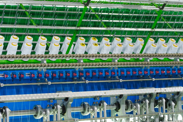 Fototapete - A machine is weaving a fabric with many different colored threads. The machine is blue and white