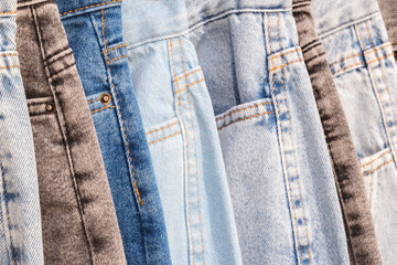 Aufkleber - A row of jeans with different colors and patterns. The jeans are hanging on a rack