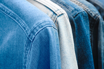 Aufkleber - A row of denim jackets are hanging on a rack. The jackets are all different shades of blue and white