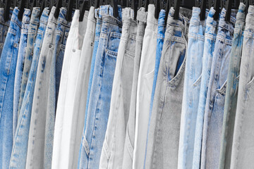 Aufkleber - A row of jeans with different colors and patterns. The jeans are hanging on a rack