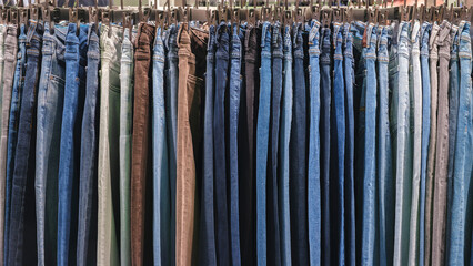 Aufkleber - A row of jeans with different colors and patterns. The jeans are hanging on a rack