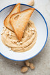 Blue and white plate with peanut butter and toasts, vertical shot on a beige stone background, elevated view, middle close-up