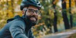 A bearded cyclist in a helmet and glasses smiles. Portrait of a biker in the park. Generative AI.